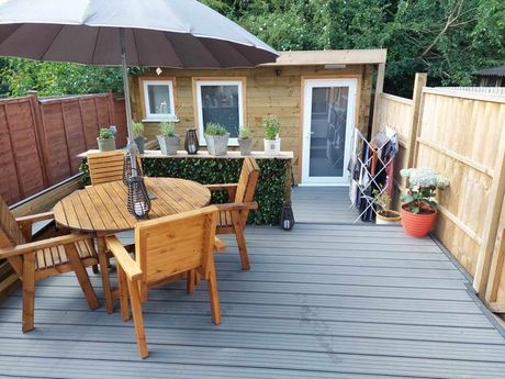 Garden building with a table, chairs, decking, fencing, and a summer house